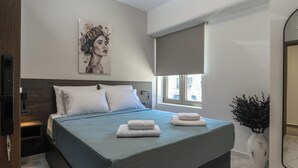 A modern bedroom with a large bed, a bedside table, a wall-mounted TV, a window with a blind, and a decorative vase.