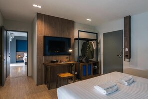 Hotellihuone, jossa on sänky, työpöytä, televisio, vaatekaappi ja kylpyhuone.
