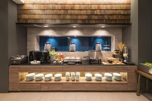 Montaje tipo bufé con una exhibición central de frascos decorativos, diversos alimentos y platos apilados ordenadamente.