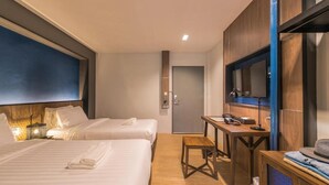 A hotel room with two beds, a desk, a television, and a door. - L Nimman Boutique Hotel (Chiang Mai)
