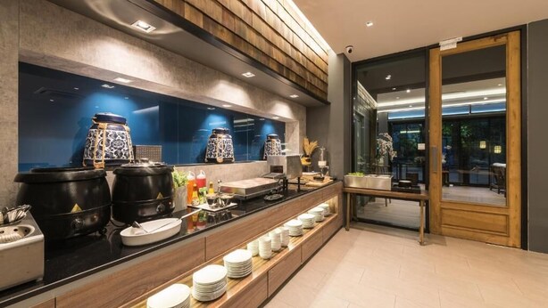 A modern hotel kitchen with a long counter, black pots, and neatly stacked plates. - L Nimman Boutique Hotel (Chiang Mai)