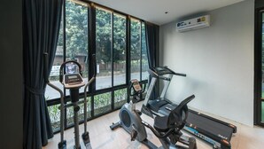 A home gym with a treadmill, stationary bike, and elliptical machine. - L Nimman Boutique Hotel (Chiang Mai)