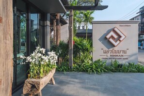 Señal del Chiang Mai Boutique Hotel, con un diseño moderno que incluye un logotipo y escritura tailandesa.