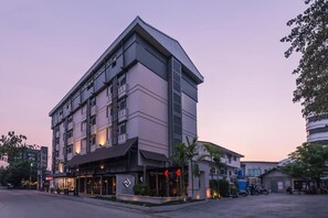 Un hotel moderno con una entrada destacada en esquina, varios pisos y techo plano.