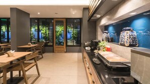 A modern restaurant with wooden tables and benches, a counter with food and drink items, and decorative blue and white vases. - L Nimman Boutique Hotel (Chiang Mai)