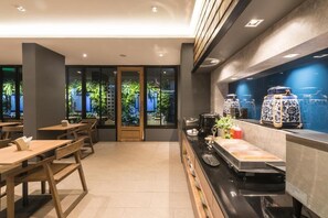 A modern restaurant with wooden tables and benches, a counter with food and drink items, and decorative blue and white vases. - L Nimman Boutique Hotel (Chiang Mai)