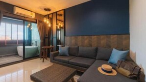 A modern living room with a sofa, a coffee table, and a hat on the sofa. - L Nimman Boutique Hotel (Chiang Mai)