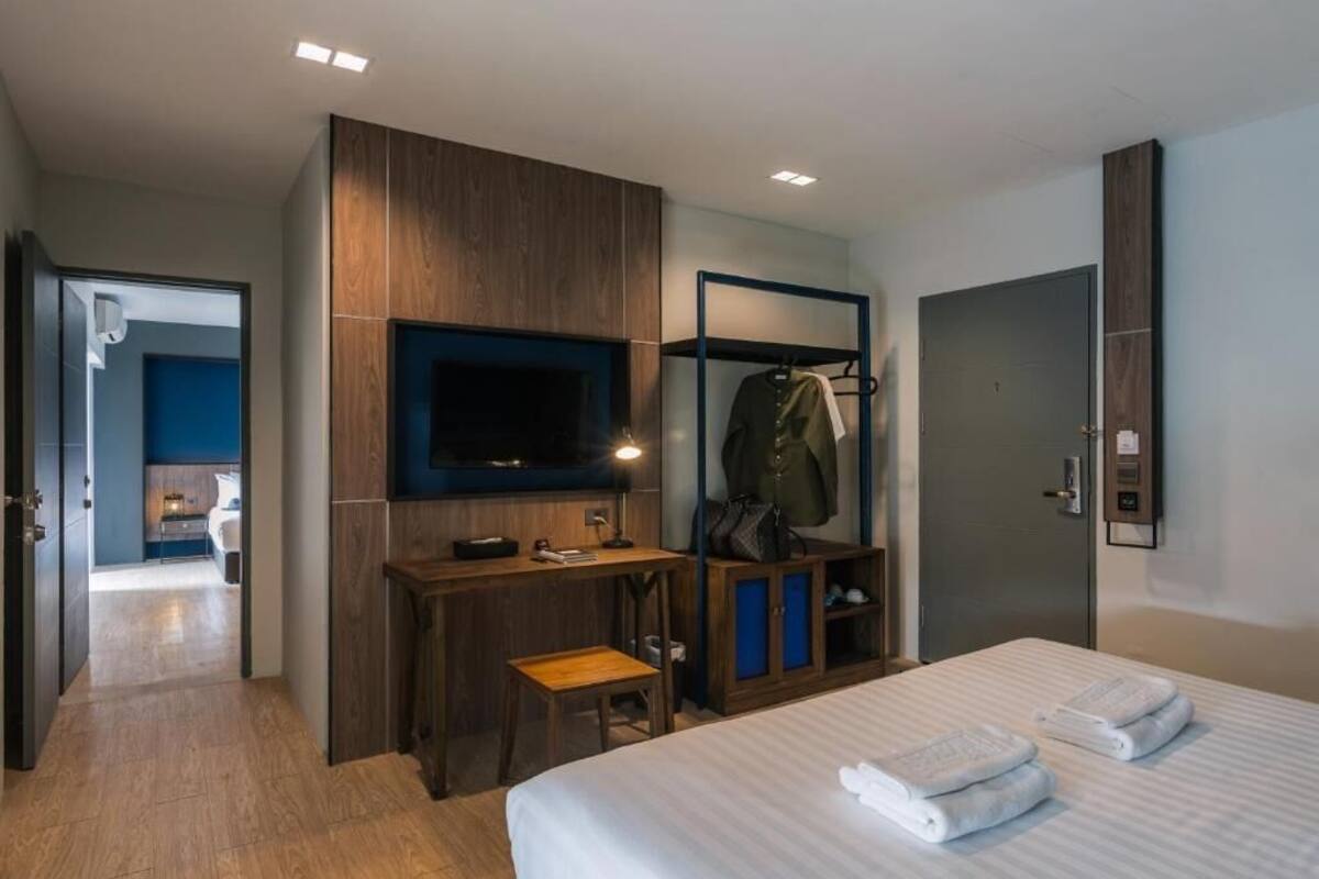 A hotel room with a bed, a desk, a TV, a wardrobe, and a bathroom.