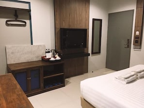 A hotel room with a bed, a wooden desk with a flat-screen TV, a mirror, and a wardrobe. - L Nimman Boutique Hotel (Chiang Mai)