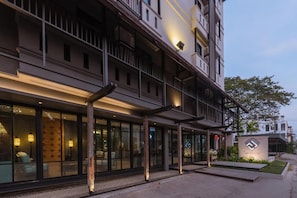 Un hotel moderno con un área de estar exterior cubierta y un letrero que indica un restaurante.