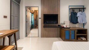 A modern hotel room with a wooden cabinet, a flat-screen TV, a desk, and a clothing rack. - L Nimman Boutique Hotel (Chiang Mai)