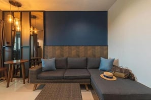 Una sala de estar moderna con un sofá modular, una pequeña mesa redonda y una lámpara colgante.