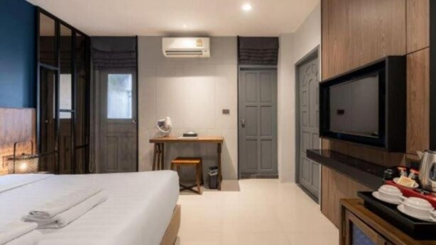 A modern hotel room with a large bed, a desk, a television, and a wardrobe. - L Nimman Boutique Hotel (Chiang Mai)