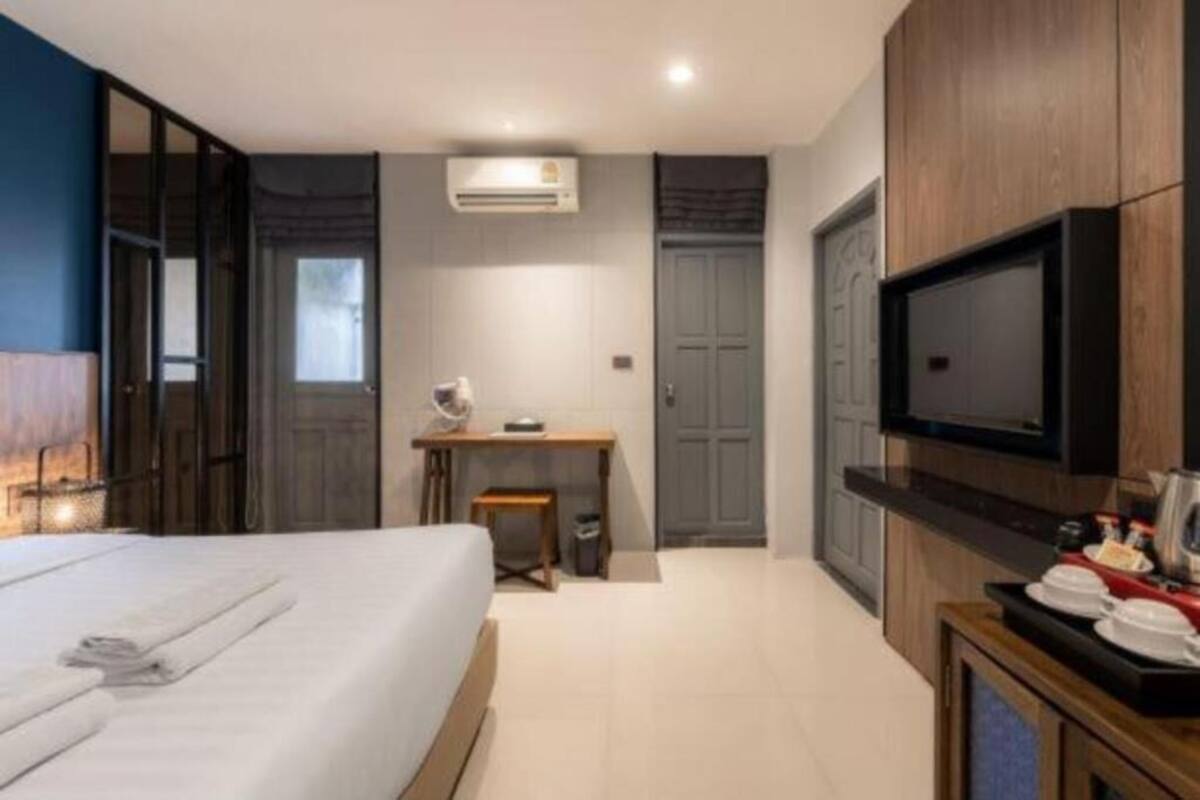 A modern hotel room with a large bed, a desk, a television, and a wardrobe.