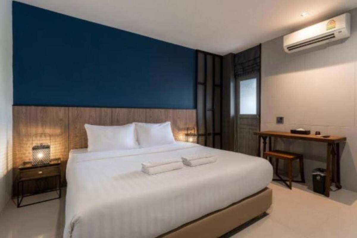 Una habitación de hotel moderna con una cama grande, un escritorio y un aire acondicionado.