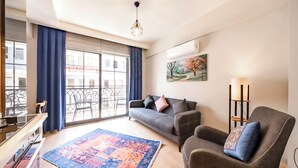 Un salon avec un canapé, un fauteuil et un tapis à motifs.