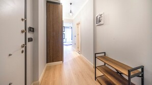 Un couloir avec un banc en bois, une porte dotée d’une poignée moderne et un luminaire suspendu.
