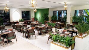A spacious restaurant with multiple tables and chairs, green plants, and modern lighting fixtures. - Wow Amazing BurjKhalifa Sea SunSet Ship (Dubai)
