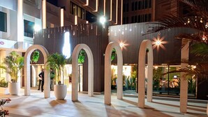 Un espacio interior amplio con pilares imponentes, plantas en macetas y un diseño arquitectónico moderno.