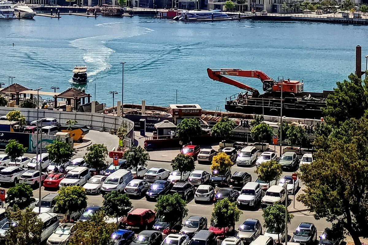 Un paisaje urbano con un puerto deportivo, barcos y una grúa.
