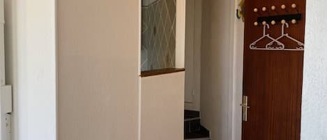 Un pasillo con una puerta de madera, un perchero y una escalera que conduce a otra habitación.