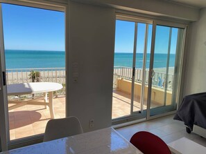 Ein Zimmer mit einer großen Schiebeglastür, die auf einen Balkon mit Meerblick führt.