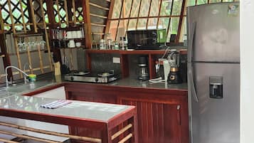 Uma cozinha compacta com geladeira, micro-ondas, fogão e cafeteira.