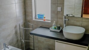 A modern bathroom with a white sink, a large mirror, a window, and a bidet. - Apartament Sea view Concorde (Portimão)