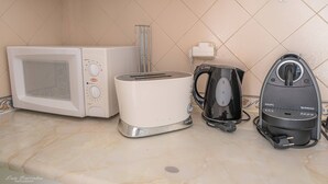 A kitchen with a microwave, toaster, kettle, and coffee maker on a tiled countertop. - Apartament Sea view Concorde (Portimão)