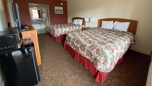 A hotel room with two beds, a desk with a computer, a mirror, and a bathroom door. - Travel Inn San Antonio (San Antonio)