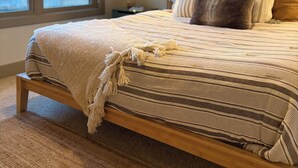 A bedroom with a bed, a window, and a wall-mounted light fixture. - Spacious 3BR Retreat with Mt. Views, Walk to the lake. 30 days stay! (Whitefish)