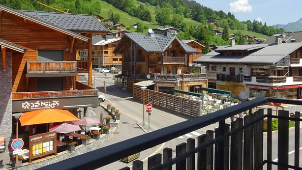 A wooden building with a restaurant sign, a street with a no entry sign, and a view of green hills in the background. - Spacious 2-Room Apt in Les Gets Center - Sleeps 4, WiFi, Linens Included, Near Ski Lifts (Les Gets)