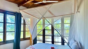 A bed with a canopy, large windows, and a ceiling fan. - Silver Rock Hotel (Malindi)