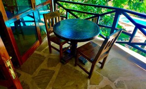 Una mesa redonda con sillas, un vidrio y vistas a follaje.