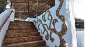 Staircase leading to a covered area with a decorative stone pattern and metal framework.