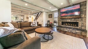 A spacious living room with a stone fireplace, a large flat-screen TV, and a cozy seating area. - 3 Bedroom Lake View Condo- #44 (Kings Beach)