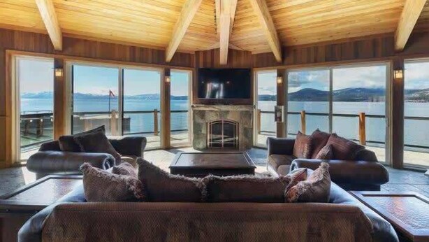 A cozy living room with a fireplace, large windows, and a view of the water. - 3 Bedroom Lake View Condo- #44 (Kings Beach)