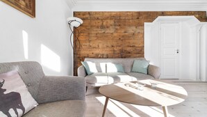 A living room with a wooden wall, a sofa, a coffee table, and a floor lamp.