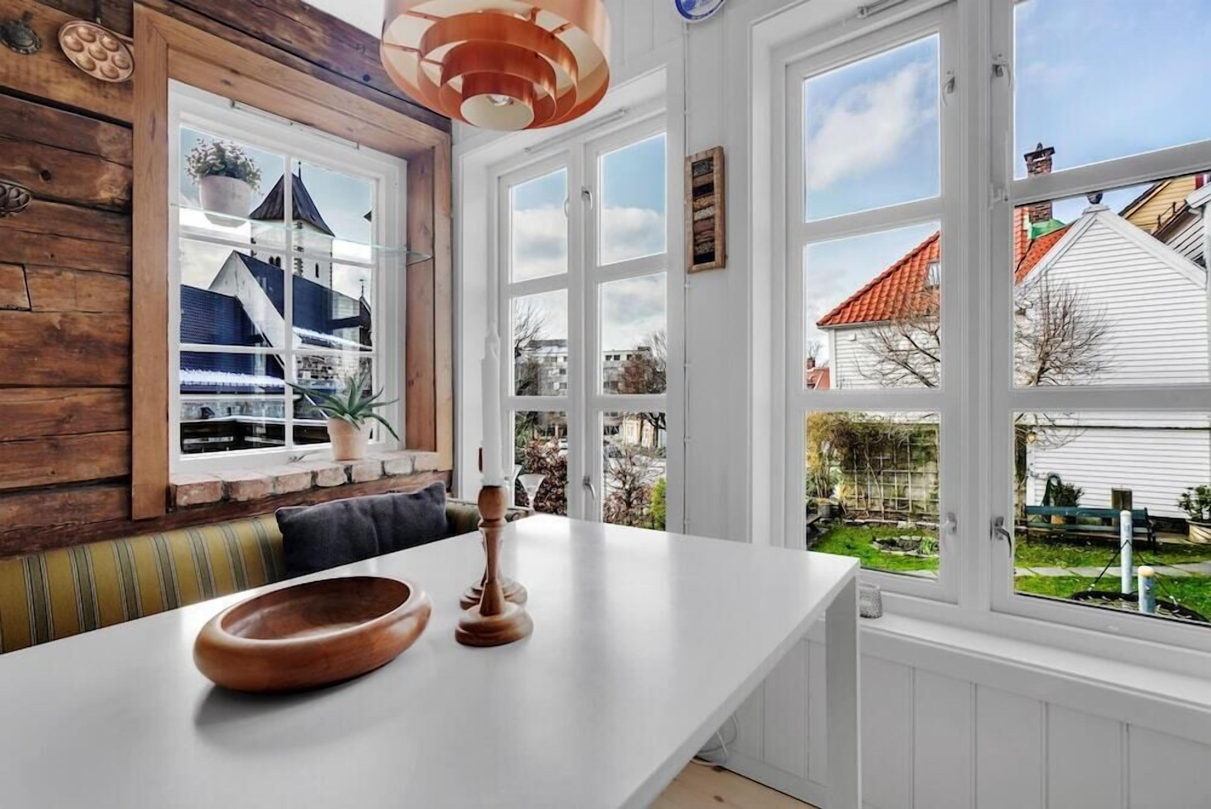 A kitchen with a large window, wooden wall paneling, and a white countertop.