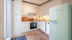 A kitchen with white cabinets, a wooden countertop, a built-in oven, and a light green refrigerator.
