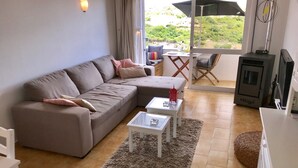 A living room with a sofa, two side tables, a glass coffee table, a fireplace, and a sliding glass door leading to an outdoor area.