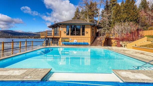 A pool area with a wooden building, a lifeguard tower, and a view of a lake. - Lakefront Condo in Kings Beach- #12 (Kings Beach)