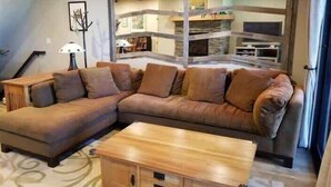 A living room with a sectional sofa, a wooden coffee table, and a staircase leading to an upper level. - Lakefront Condo in Kings Beach- #12 (Kings Beach)
