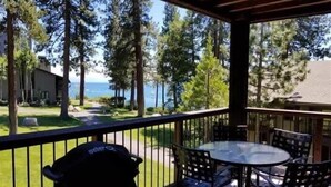 A covered outdoor area with a table and chairs, overlooking a grassy area and trees. - Lakefront Condo in Kings Beach- #12 (Kings Beach)