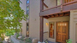 A two-story building with a wooden balcony, a stone pathway, and a door marked with the number 19. - Lakefront Condo in Kings Beach- #19 (Kings Beach)
