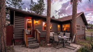 A log cabin with a porch, outdoor seating, and a staircase leading to the entrance.