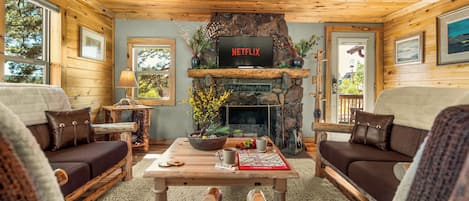 A cozy living room with a fireplace, wooden furniture, and a Netflix sign.