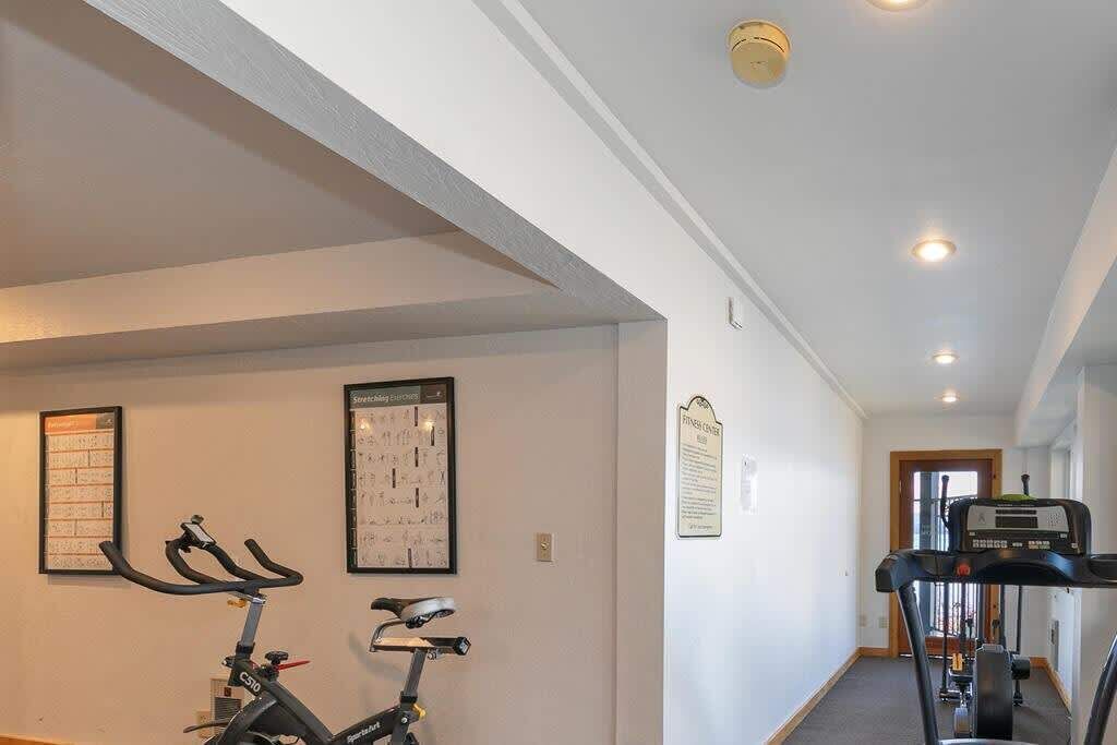 A hallway with exercise equipment, including a stationary bike and a treadmill.