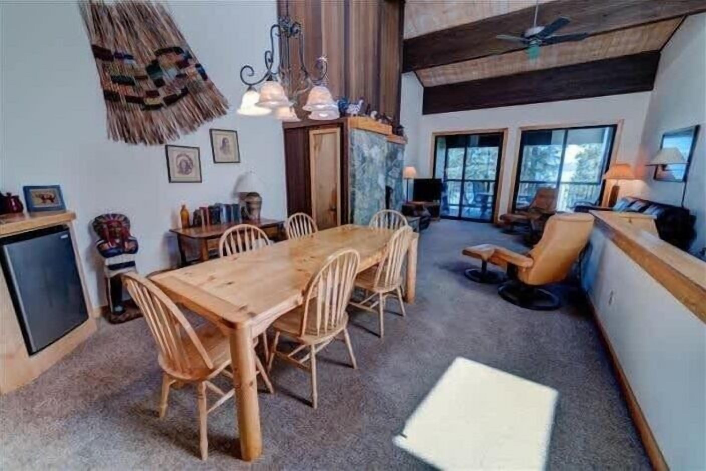 A cozy dining area with a wooden table and chairs, a small kitchen area, and a seating area with a sofa and chairs.