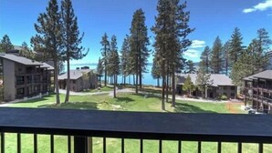 A residential area with multiple buildings, a grassy courtyard, and tall pine trees. - Lakefront Condo in Kings Beach- #26 (Kings Beach)